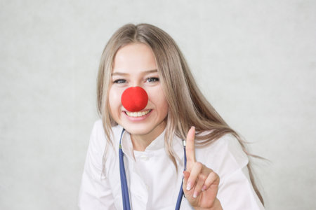 a pediatrician with a red nose. doctor blond girl with stethoscope in hands. beautiful girl. on a white background. clown noseの写真素材