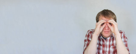 business concept. the man looks through binoculars. man in plaid shirt with a place under the textの写真素材