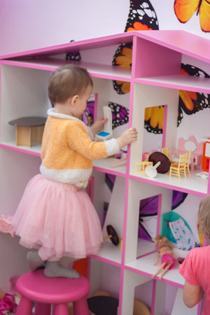 Dollhouse. little girl in all pink plays in dollsの写真素材