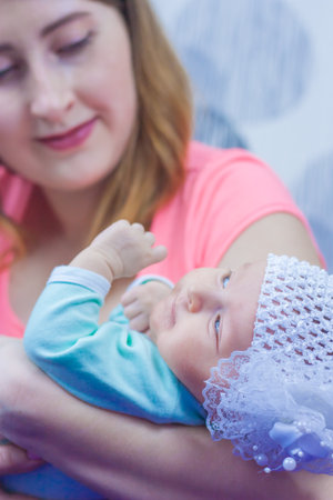 newborn baby girl. Cute baby with mom. care for a newborn baby. girl in a hat with a bow. a family. vertical sheet orientationの写真素材