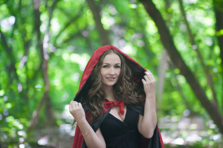 a witch in a red hat in the middle of a forest. attractive girl halloween magic. fairy smileの写真素材