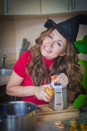 Halloween. preparation for a party. witch coven. the witch in the kitchen. potatoes are rubbed on a...