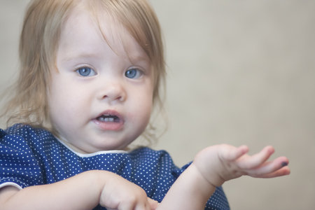 question for children. the child is ripping. cute little girl in a blue dress in polka dots. with blond hairの写真素材