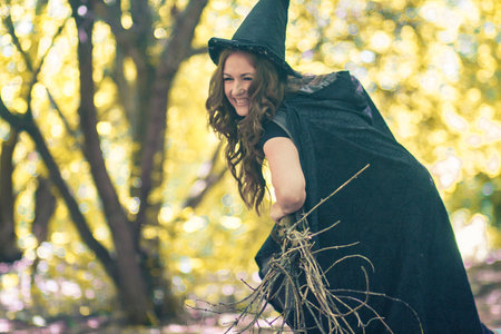 The Witch Halloween. beautiful witch with a broom in the hands among the forestの写真素材