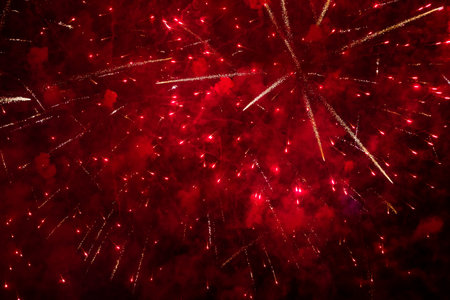 Intense red fireworks filling night sky with bright exploding trails, rich saturated tones suitable for festive backgrounds and celebrations.の写真素材