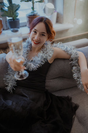 Festive celebration mood, close-up portrait Smiling woman, warm light, plants near window, joyful evening atmosphere, elegance and glamour lifestyle photo, sparkling details.の写真素材
