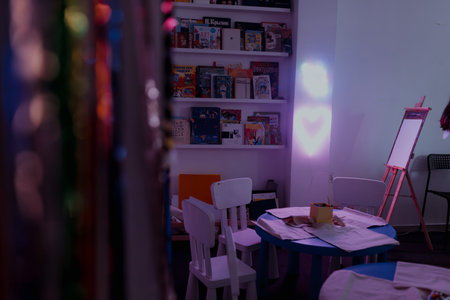 Child-focused craft area featuring blue tables, small white chairs, canvas bags prepared for...