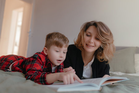 Warm daylight shows mother reading storybook while boy lies beside her pointing page, cozy bedroom...