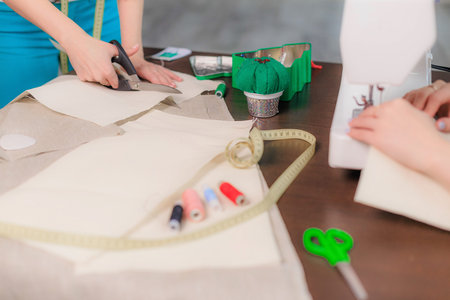 Sewing workspace with fabric cutting and machine stitching. Hands working on handmade textile...