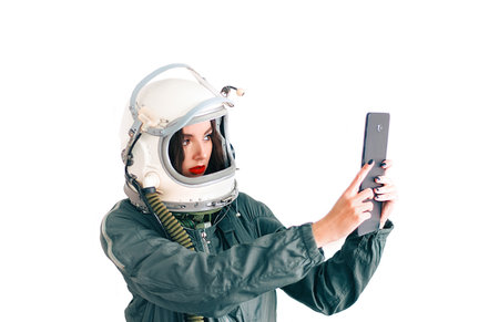 Astronaut girl in space helmet. Isolated on white background. Young girl in an astronaut suit. Space helmet. Background wallpaper. Another world. Space people. Cosmic atmosphere. Free space for text.の写真素材
