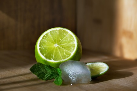 Fruit lime with mint and ice on a wooden surfaceの写真素材