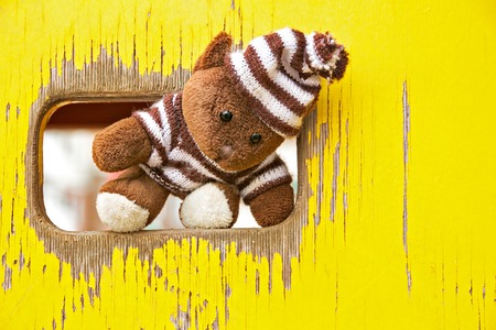 Soft toy bear stands in the opening of the yellow wall on playgroundの写真素材