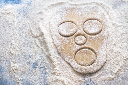 raw dough in shape of face rolled out on a flour covered tableの写真素材