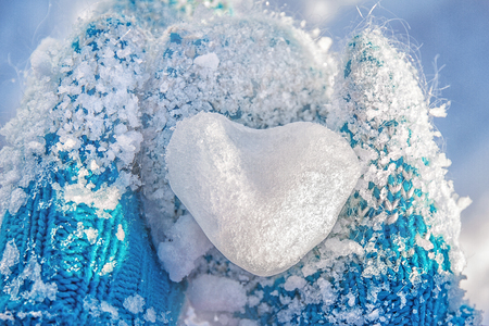 ice small snow heart in childrens hands dressed in blue mittensの写真素材