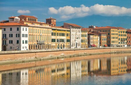 old Italian houses on the embankment of the river Arno, reflected in the water on a sunny day in the city of Pisa, Tuscany, Italyの写真素材