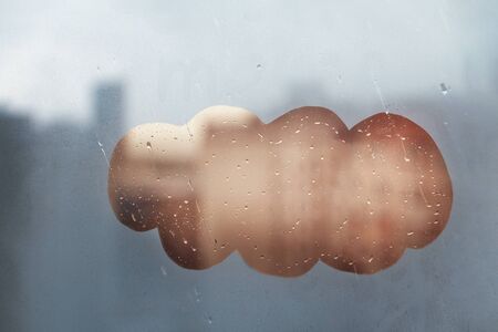 Blurred spot cloud on foggy window spattered with drops city, blue, yellow color, copyspaceの写真素材