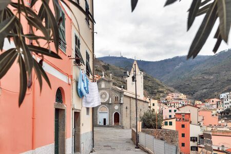 Old pink house and Basilica Church of St. John the Baptist in Riomaggiore Cinque Terre, Italy, February 2019の写真素材