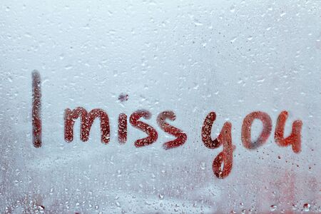 Foggy glass on window with written finger word red color I miss you concept of loneliness, sadness...