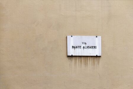 old Dante Alighieri street nameplate on ancient yellow wall in Florence in Italyの写真素材