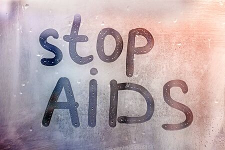 words stop AIDS with written finger on foggy blue red gradient glass on drops window concept photo...