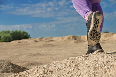 girl runs purple in leggings and sneakers shoes close-up bottom view on desertの写真素材