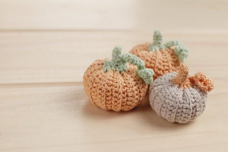 three crocheted pumpkins of orange and gray colors in handmade on a wooden table, selective focusの写真素材