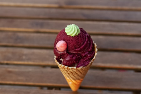 organic blueberry burgundy ice cream without sugar with meringue in waffle cone on wooden background