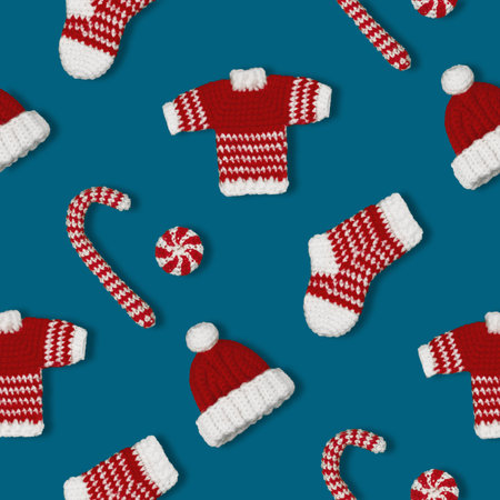 seamless pattern knitted Christmas handmade decorations sock, sweater, hat and caramel in red and white colors on blue backgroundの写真素材