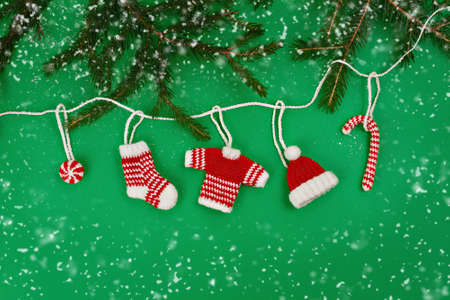 decorative knitted ornaments sock, sweater, hat and caramels in red and white color with fir-tree...