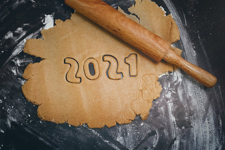 Arabic numerals 2021 painted on white flour on black table and rolling pin horizontally down, close upの写真素材