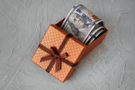 Pack of one hundred dollars banknotes in open brown box on gray concrete backgroundの写真素材