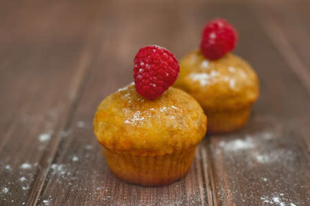 orange two carrot cupcake with raspberry on old wooden table, copy space, selective focus