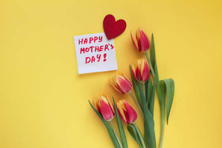 one piece of paper for notes with words Happy Mother's Day and red wooden heart, five tulips on...