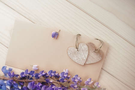 A brown envelope with two vintage wooden hearts on rustic table with flowers lupineの写真素材