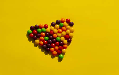 multi-colored round heart-shaped sweets on yellow backgroundの写真素材