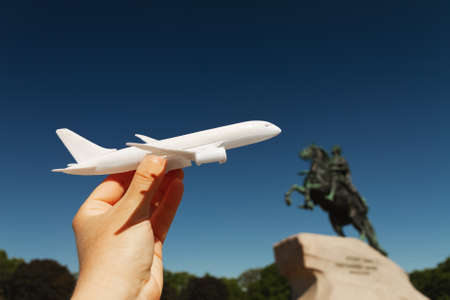 white plane in woman's palm on background Bronze Horseman Senate square in St. Petersburg, Russia on sunny day, copy spaceの写真素材