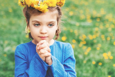 little girl in blue dress in wreath of dandelionsの写真素材