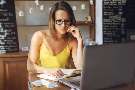 Portrait of businesswoman with laptop works remotely in cafe