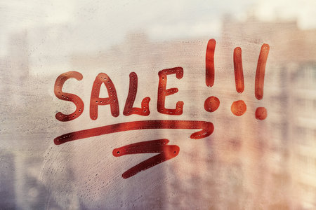 Foggy glass on window with written finger red word Sale on muddy sunset glass wet windowの写真素材