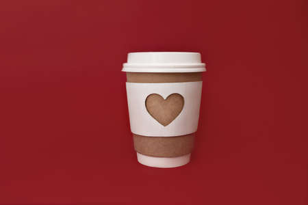 paper brown coffee cup with white cover and carved white heart on red background, copy spaceの写真素材