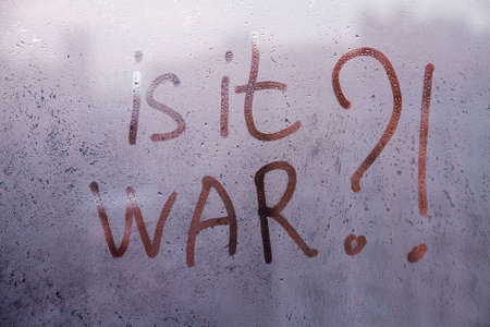 Red question Is it war are painted handwriting on dark violet window with raindrops