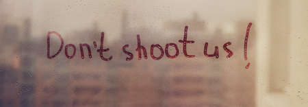 Message call Dont shoot us are painted handwriting on window with raindropsの写真素材