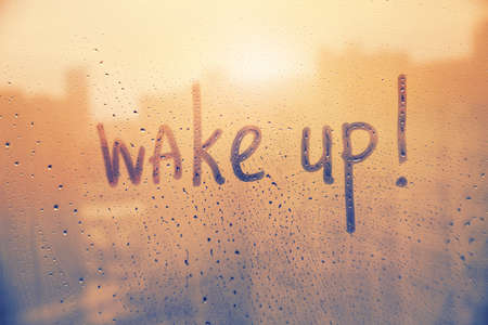 Hand drawn message Wake up on foggy glass on suset windowの写真素材