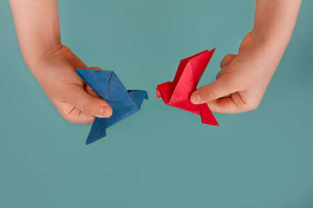 banner blue and red paper origami pigeon in children's hands on blue background, copy spaceの写真素材
