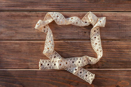 background brown wooden table and lace white square frame cotton ribbon