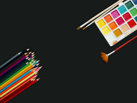 watercolor paints, brushes and multicolored pencils on black backgroundon