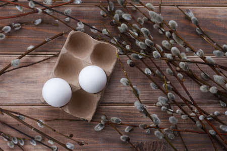 two white eggs in box and willow branches on wooden backgroundの写真素材