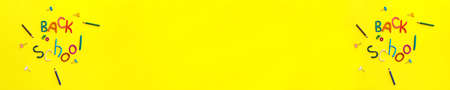 banner two words of multi-colored plasticine back to school and pens, paper clips, on yellow background top viewの写真素材