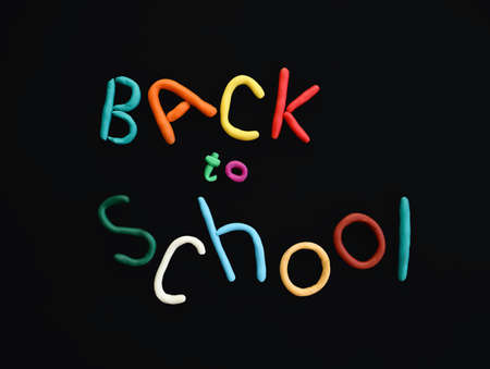 handmade words of multi-colored plasticine back to school in wry funny style on black backgroundの写真素材