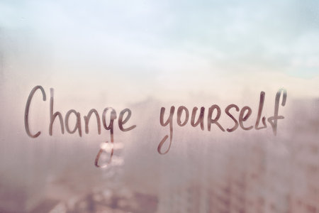 Written finger words Change yourself on foggy window on muddy glass wet window